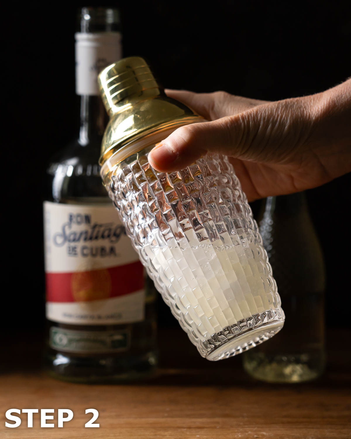 A person shaking a lime daiquiri in a cocktail shaker.