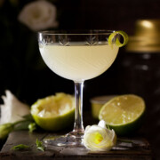 A classic daiquiri cocktail with lime zest garnish in a dark setting.