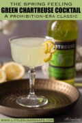 Labelled Green Chartreuse cocktail garnished with lemon zest spirals with a bottle of liqueur behind.