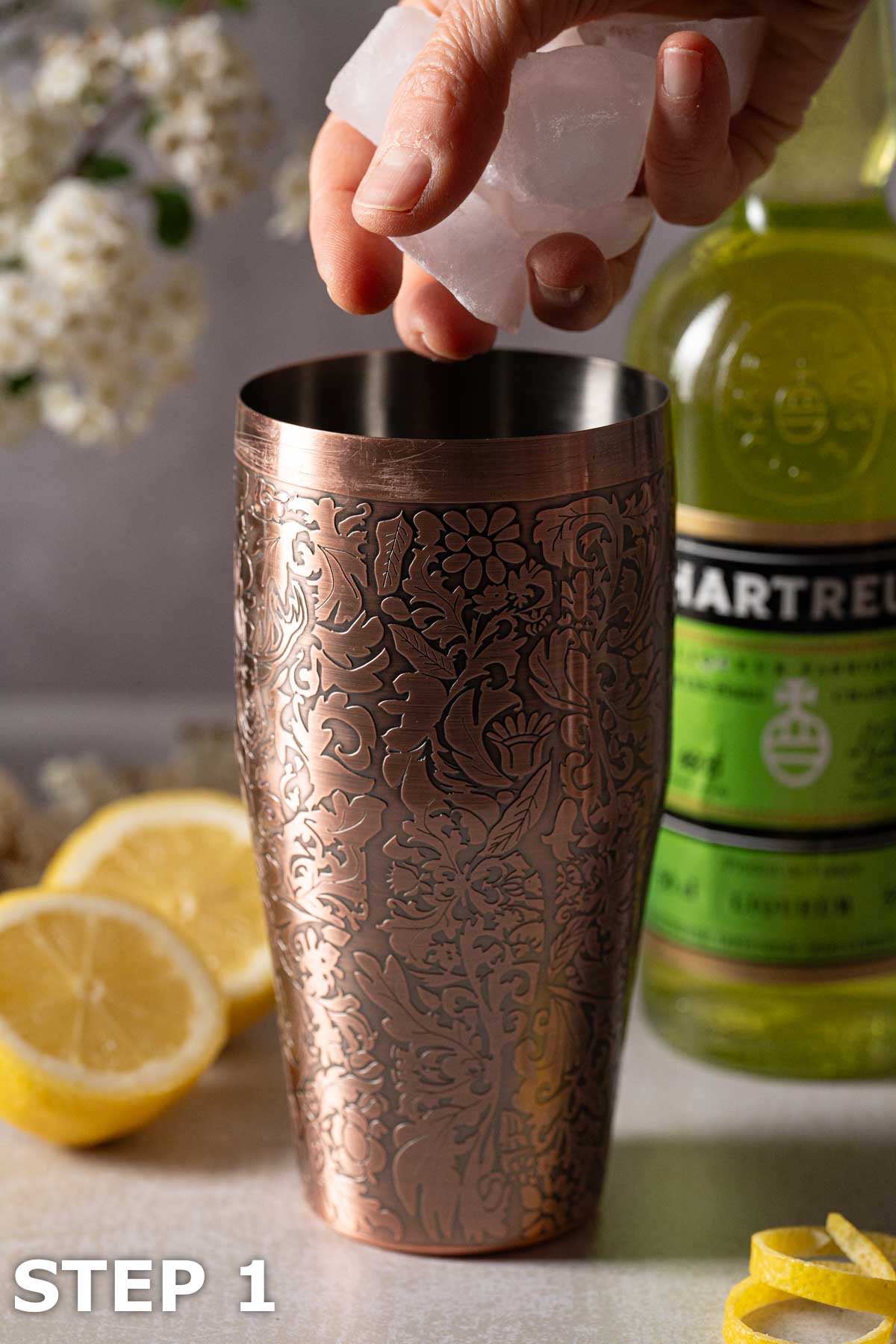 A person adding ice to an embossed copper cocktail shaker.