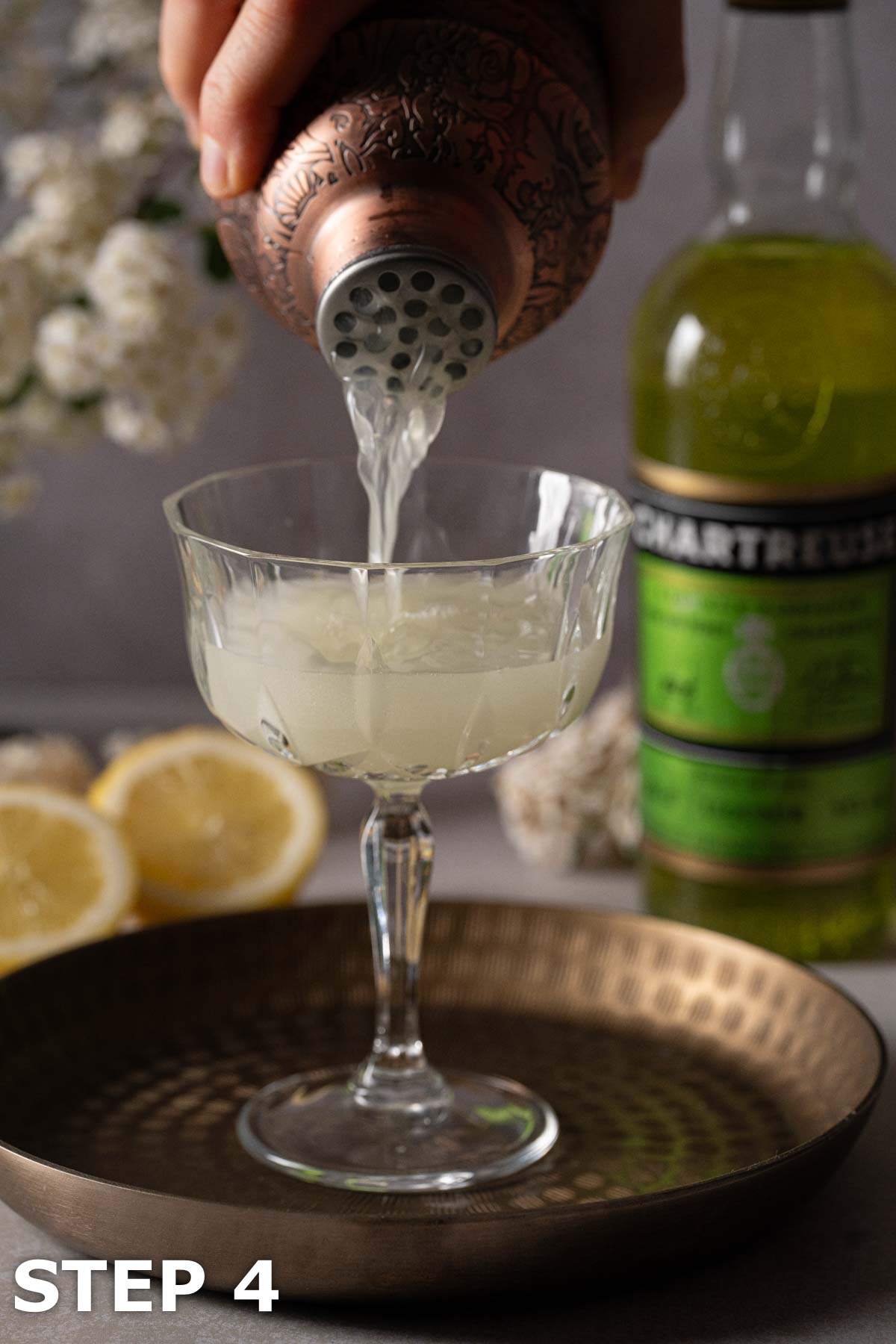 A person pouring a Spring Feeling cocktail into a cocktail glass.