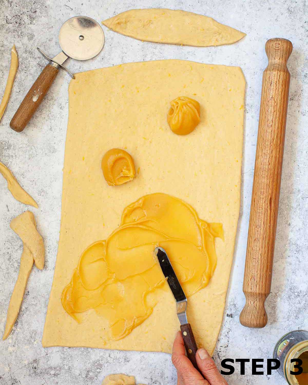 Lemon curd being spread over rolled out dough.