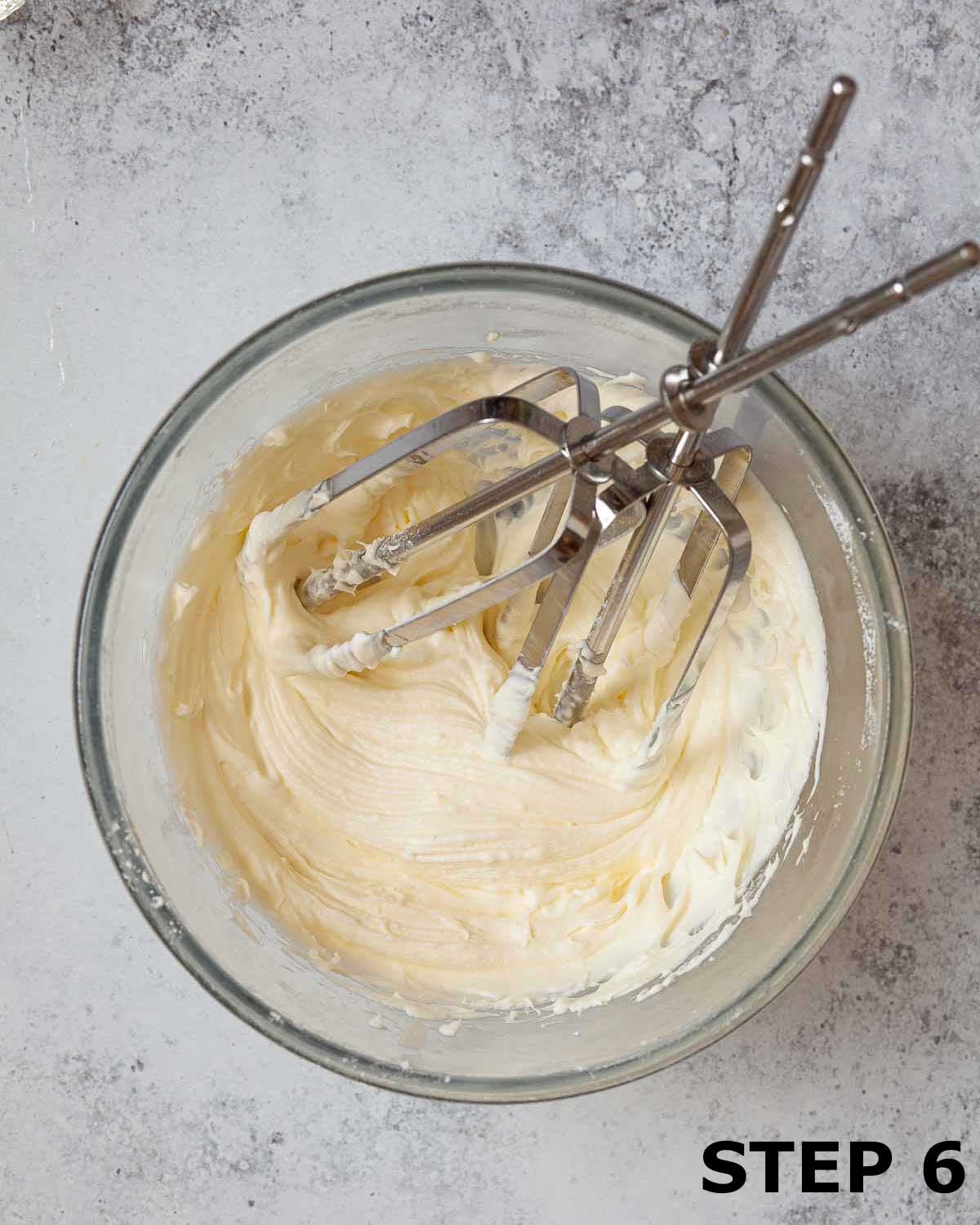 Cream cheese frosting in a mixing bowl with beaters.