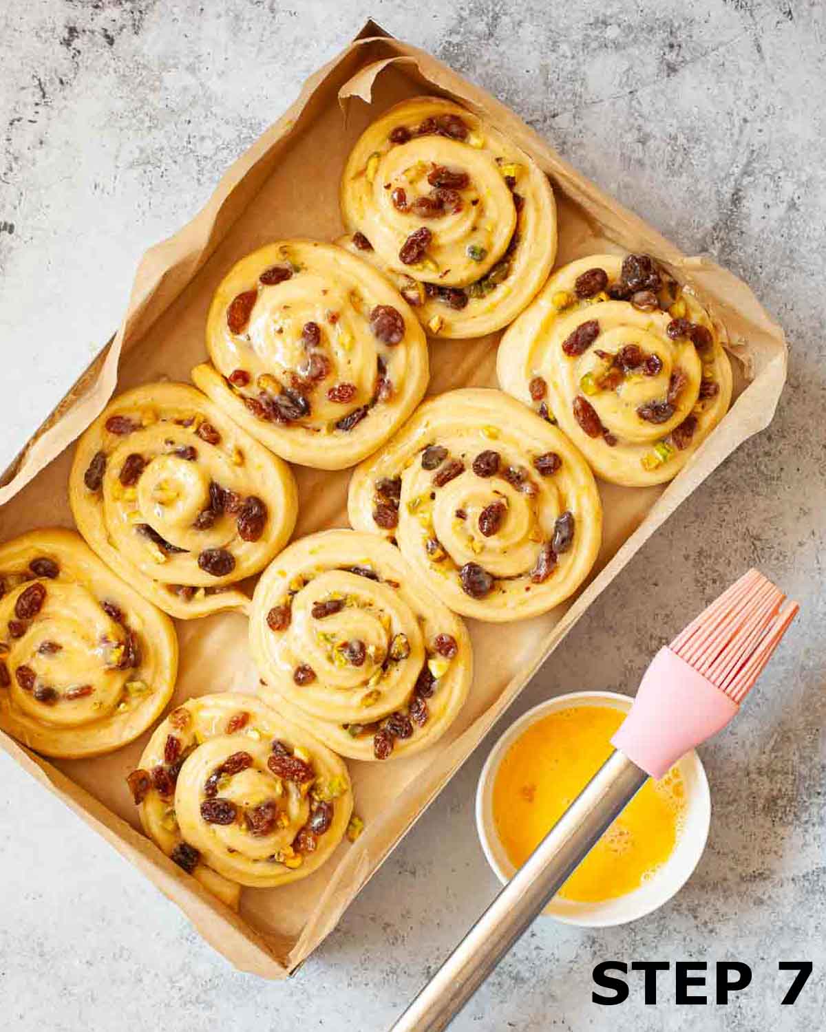 Raw lemon rolls in a baking tin with egg wash brushed on.