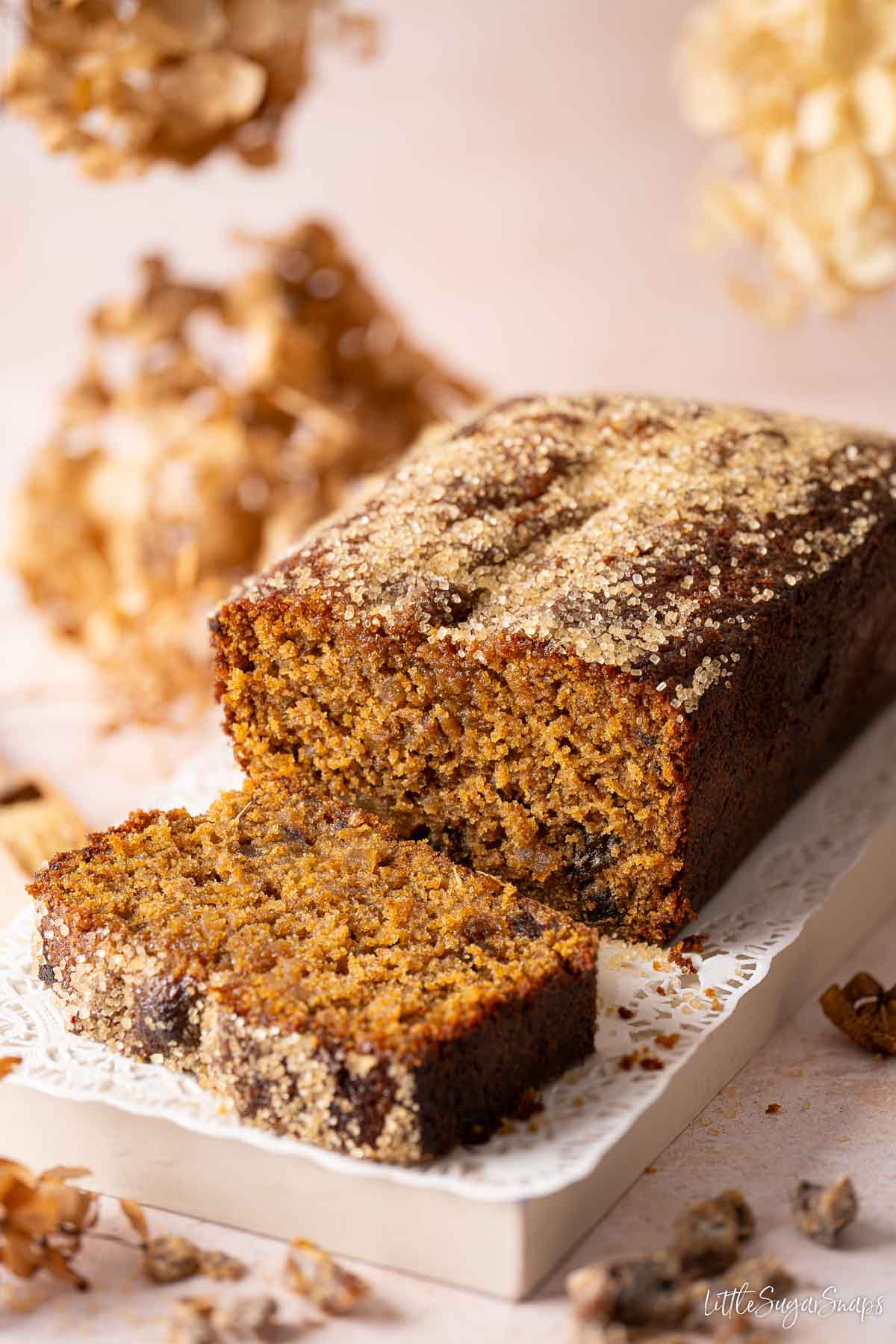 A sticky date cake with a slice cut and lying in front of the cake.