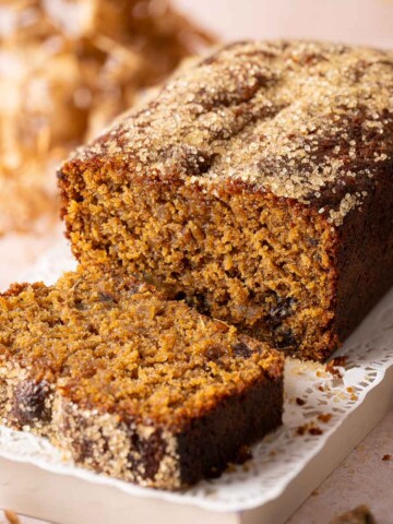 A sticky date cake with a slice cut and lying in front of the cake.