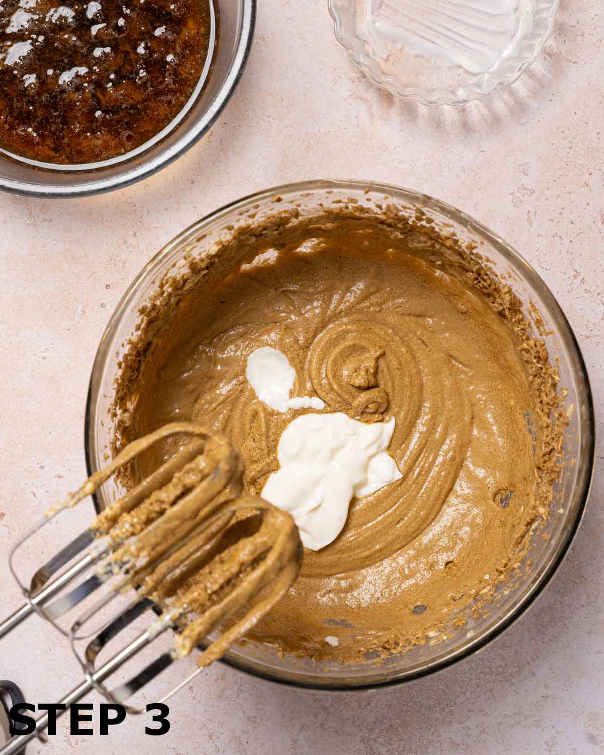 Soured cream about to be beaten into cake batter with electric beaters.