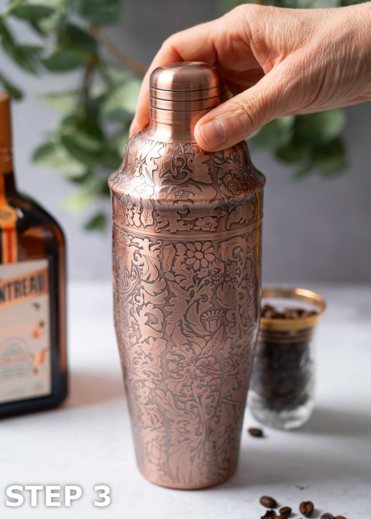 A person securing the lid on a cocktail shaker.