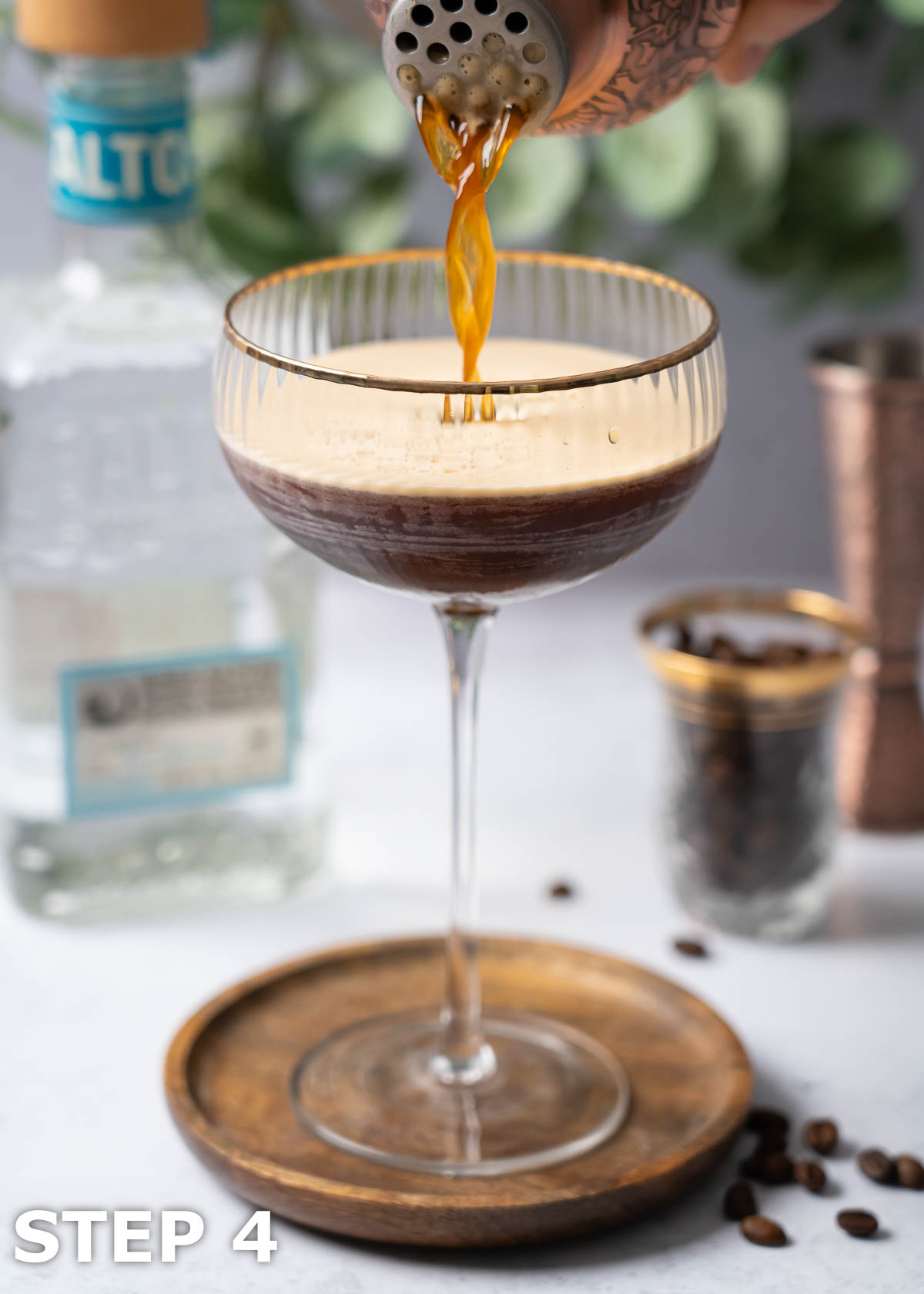 A person straining a shaken Mexican espresso martini into a cocktail glass.