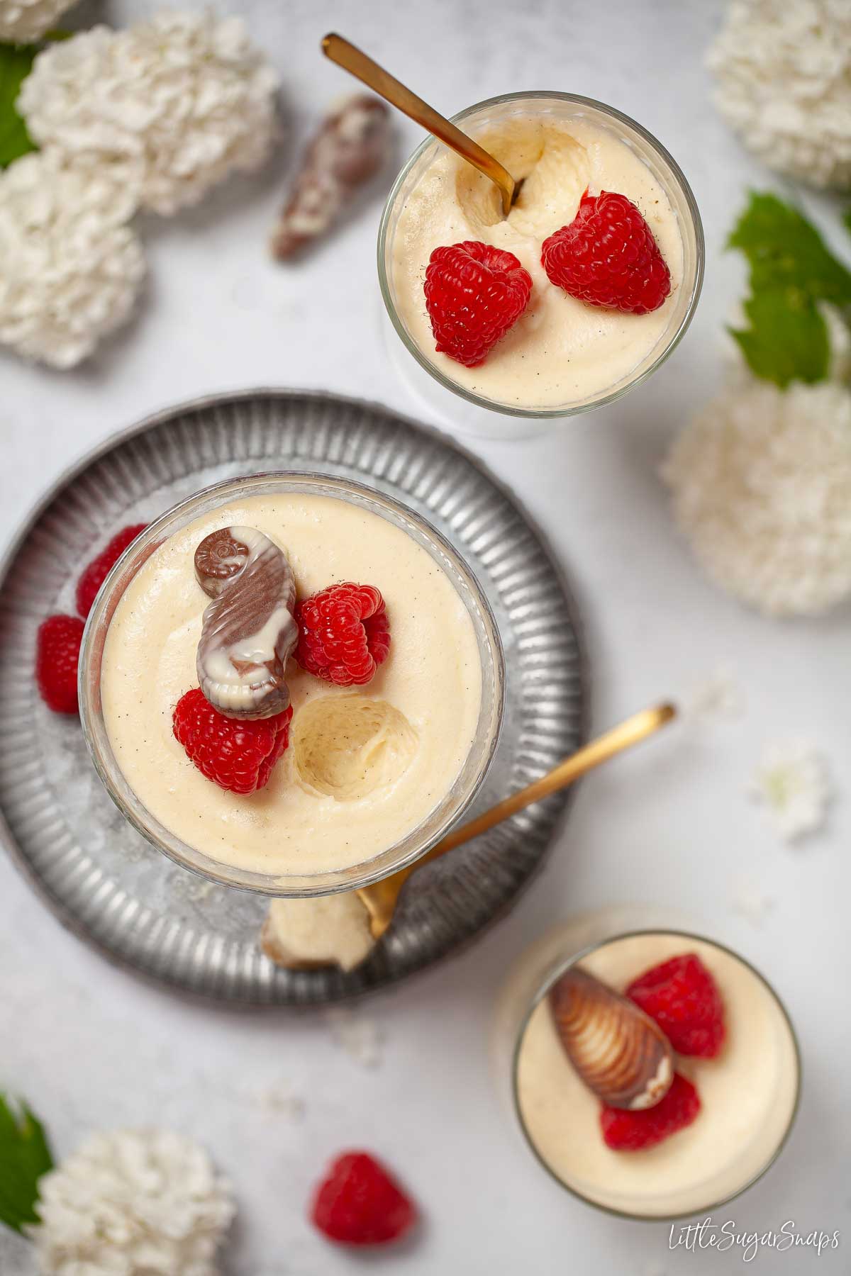 Part-eaten glasses of white chocolate mousse with chocolate and raspberry garnish.
