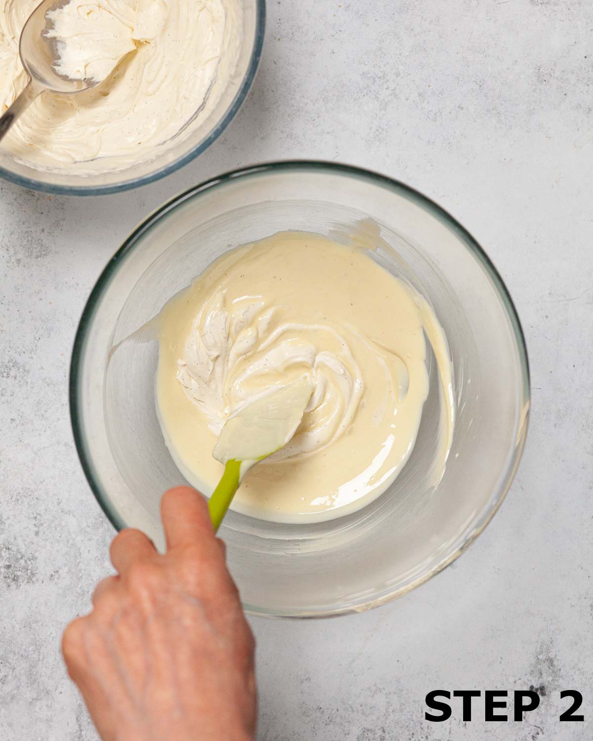 A person stirring cream into melted white chocolate to temper it.