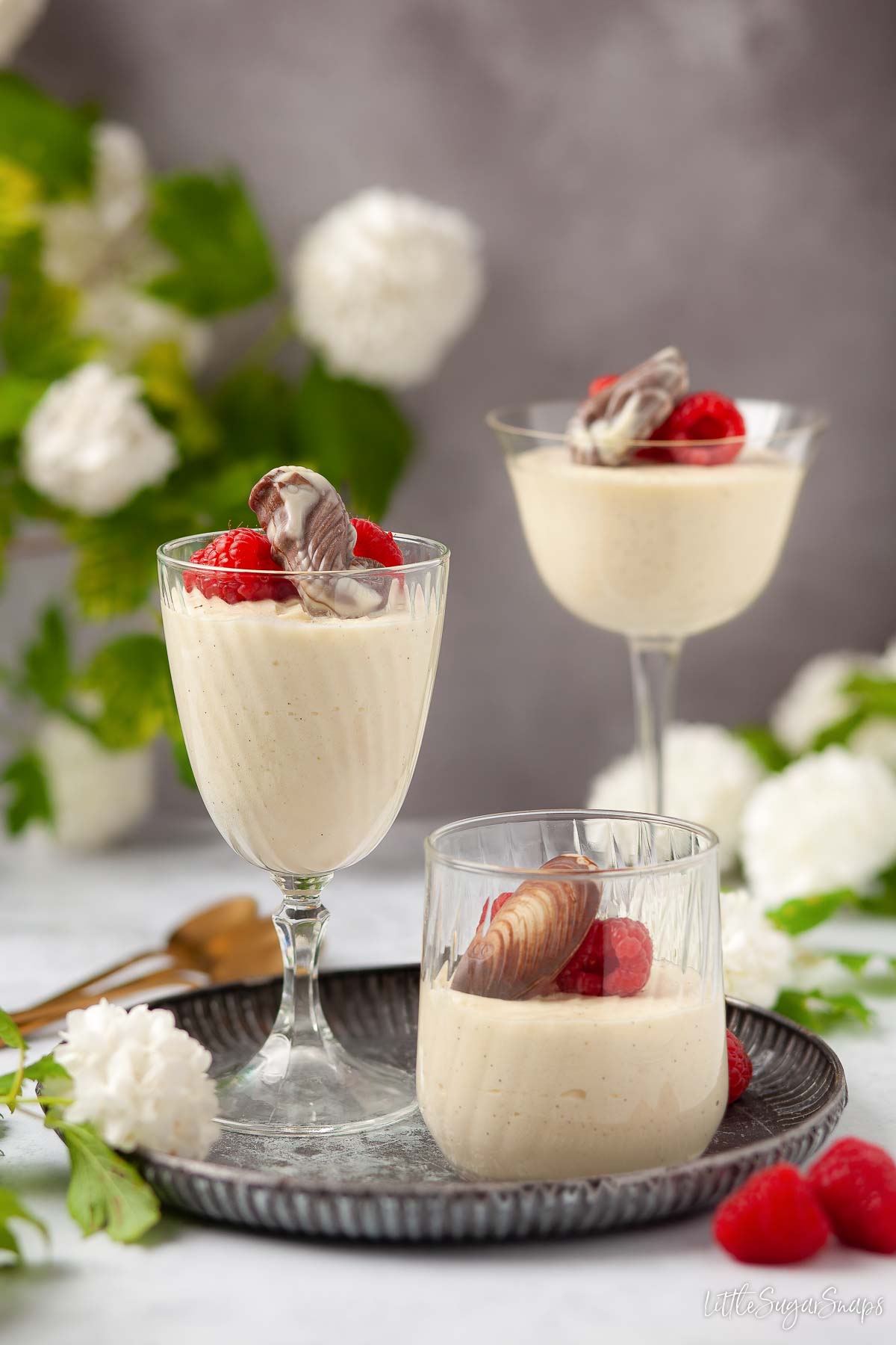 Three glasses of white chocolate mousse with chocolate and raspberry garnish.