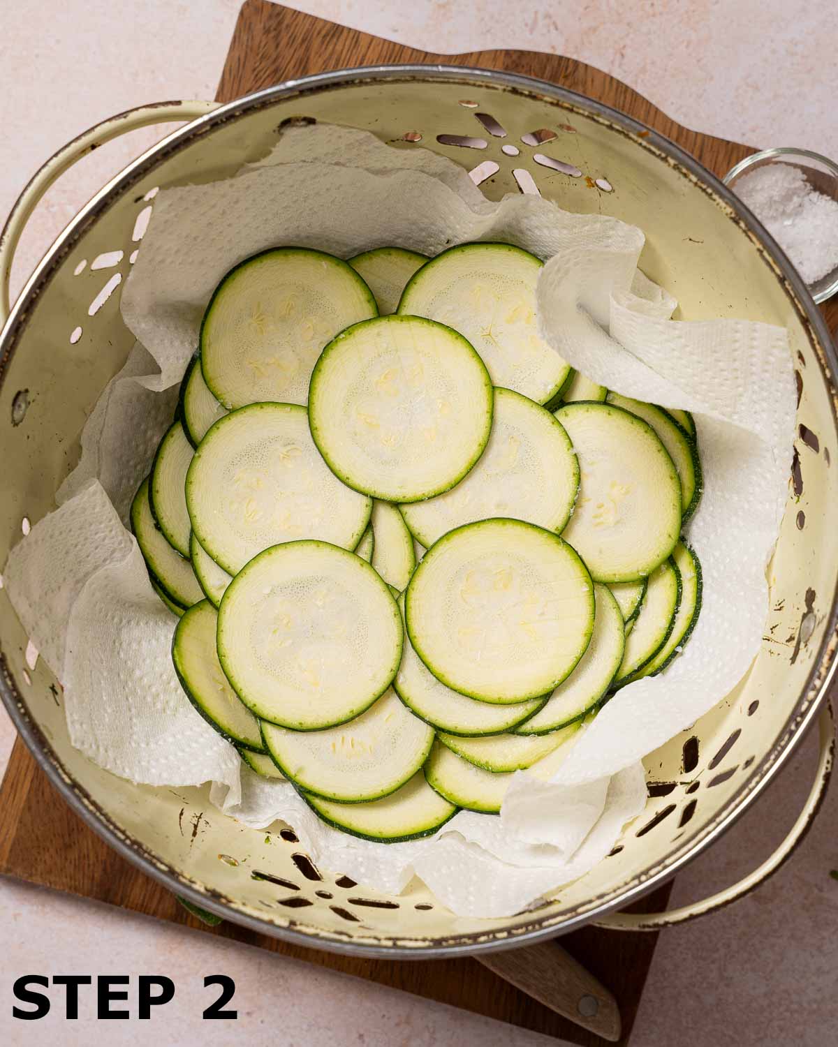 Slices of courgette sprinkled with salt in a colander.