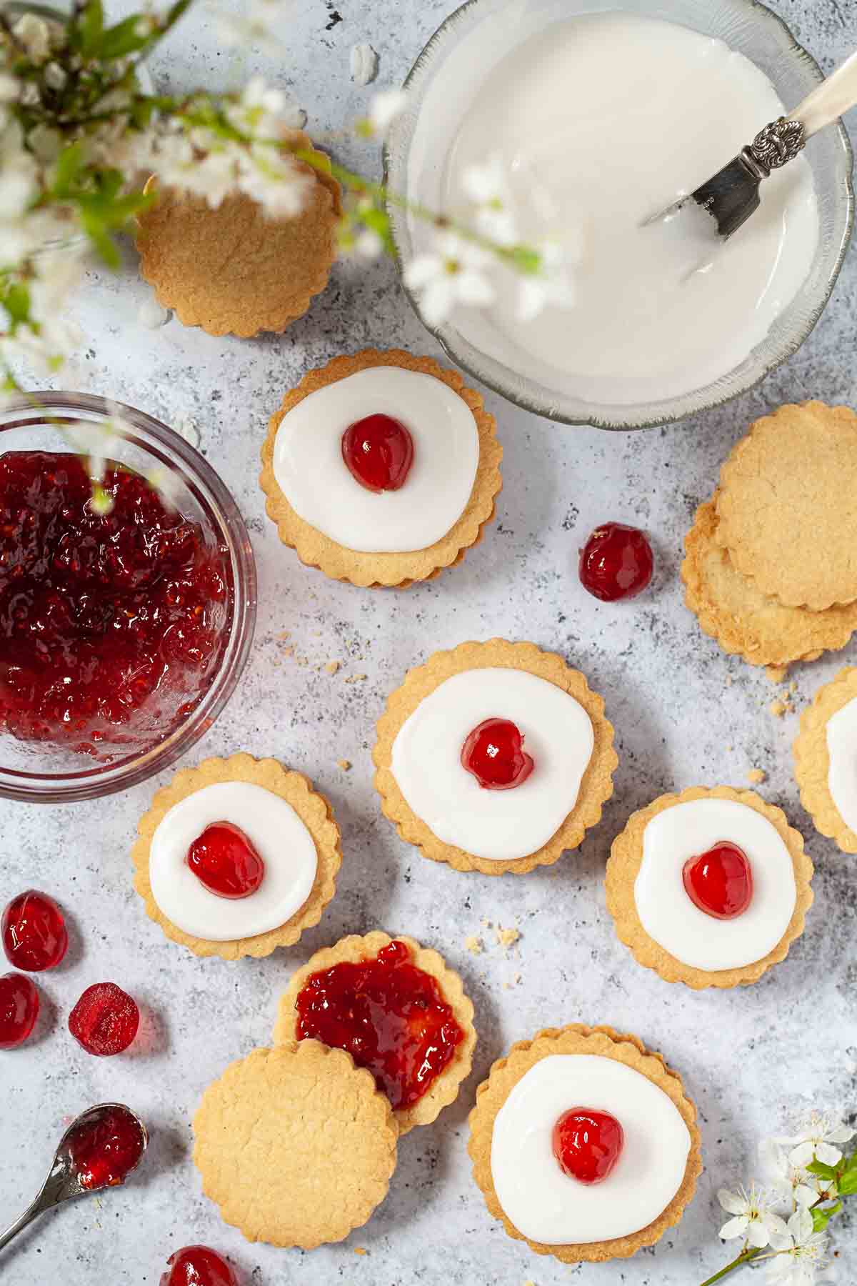 Shortbread biscuits being sandwiched together with raspberry jam and iced to make Empire cookies
