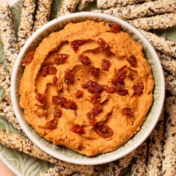 White bean dip with sun-dried tomato served with seeded breadsticks.