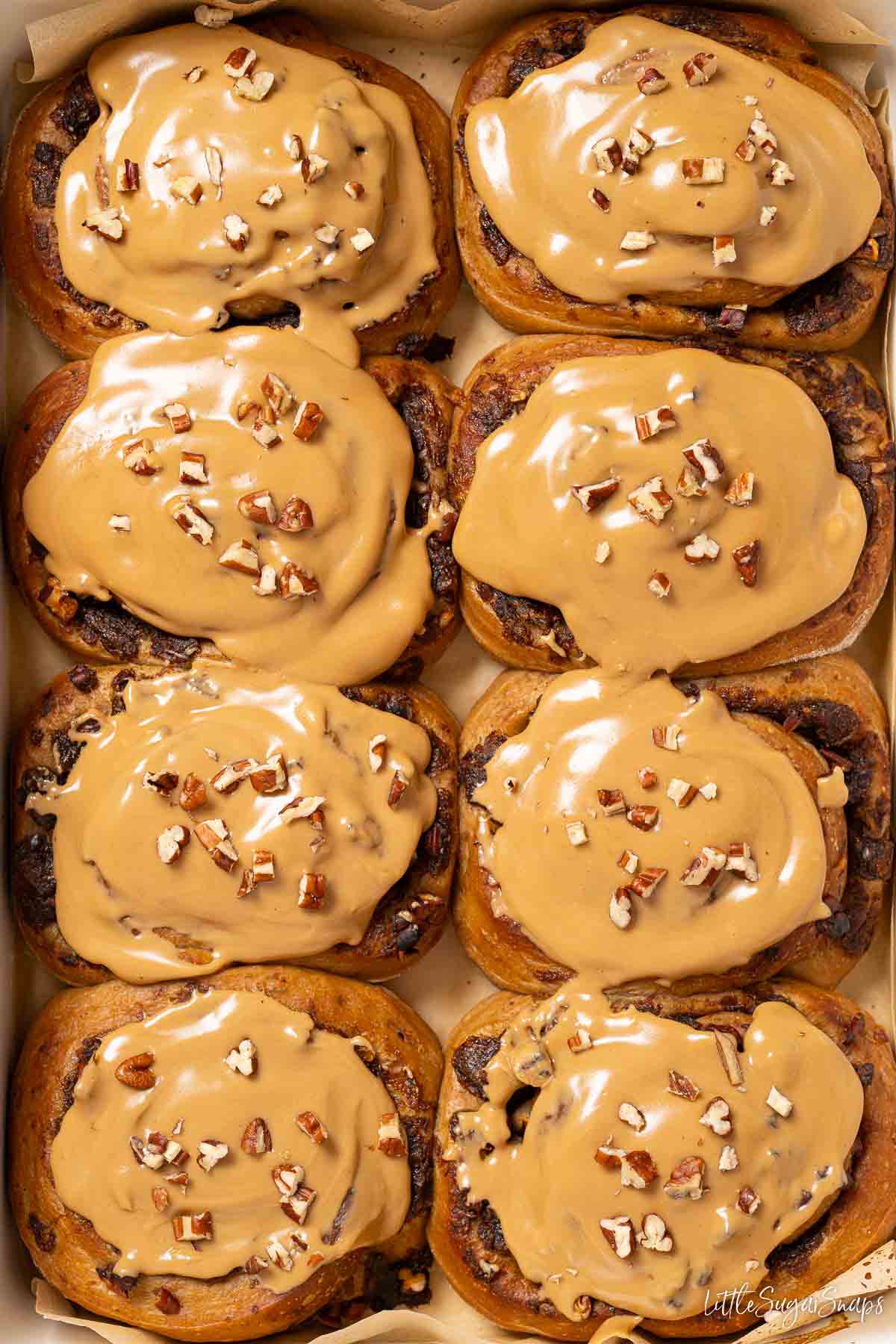 Eight coffee buns topped with coffee glaze and chopped pecan nuts.