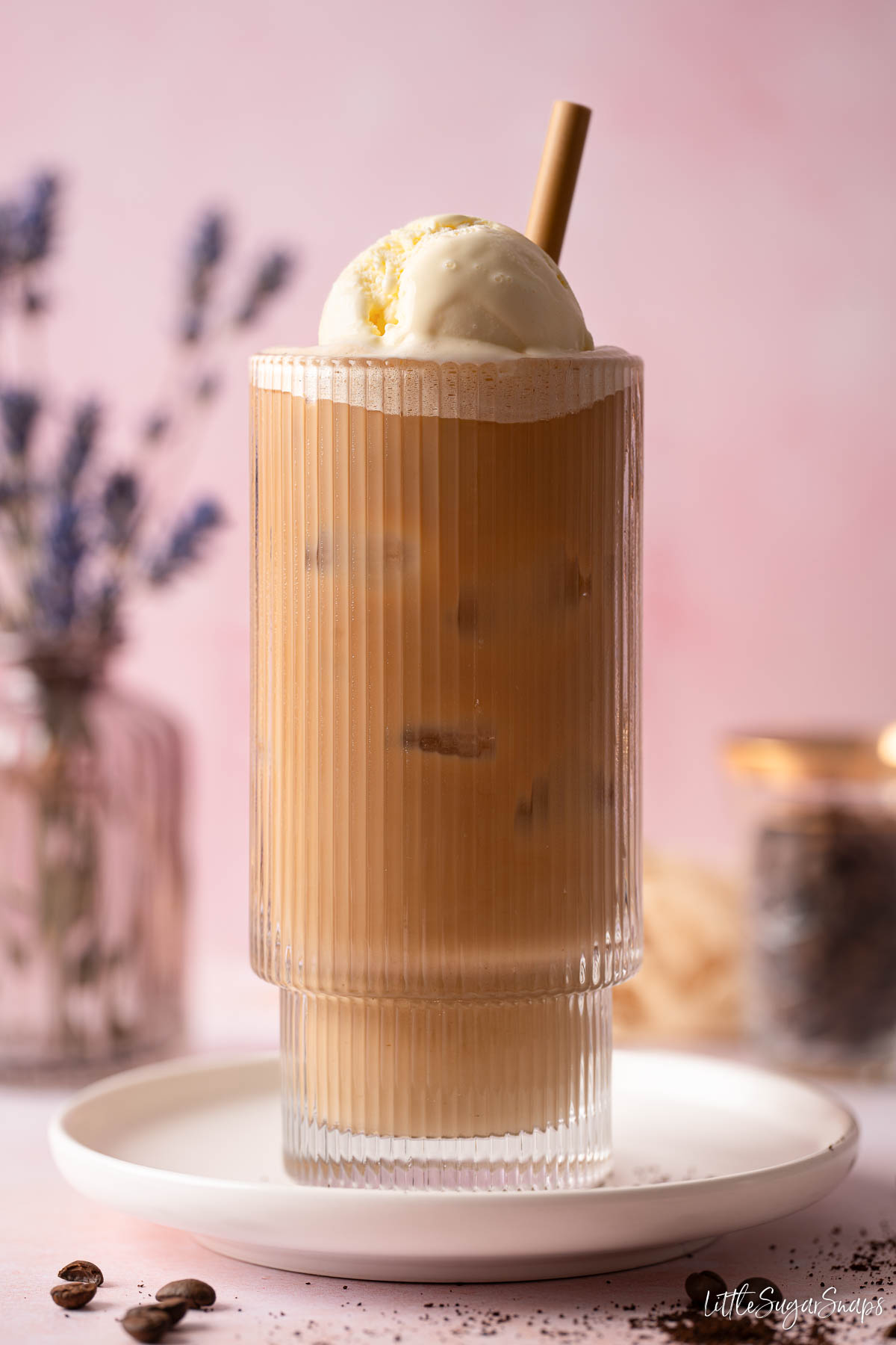 A coffee float (iced latte topped with ice cream) in a glass with a straw.