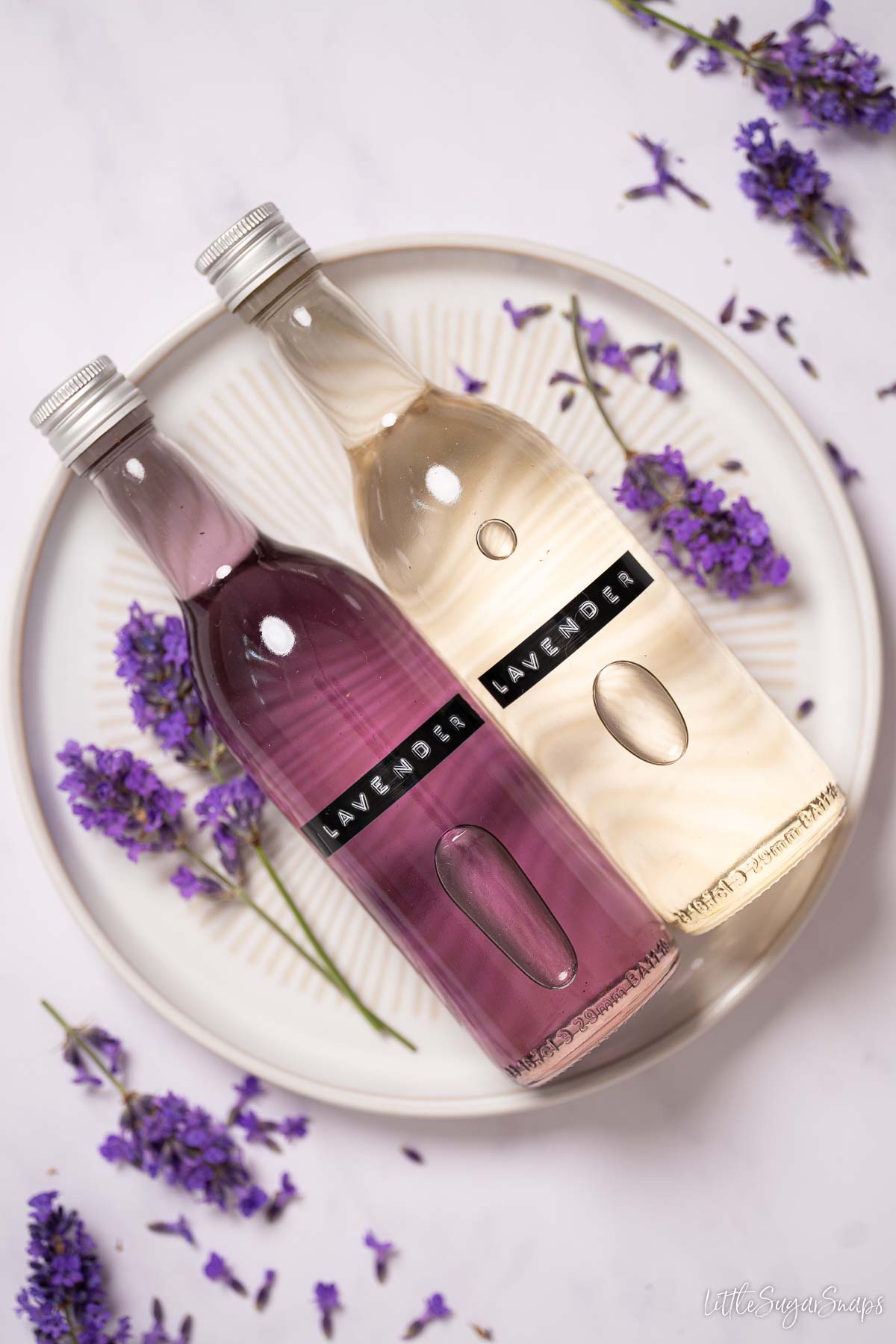 Bottles of labelled lavender simple syrup, one is clear, the other is purple coloured.