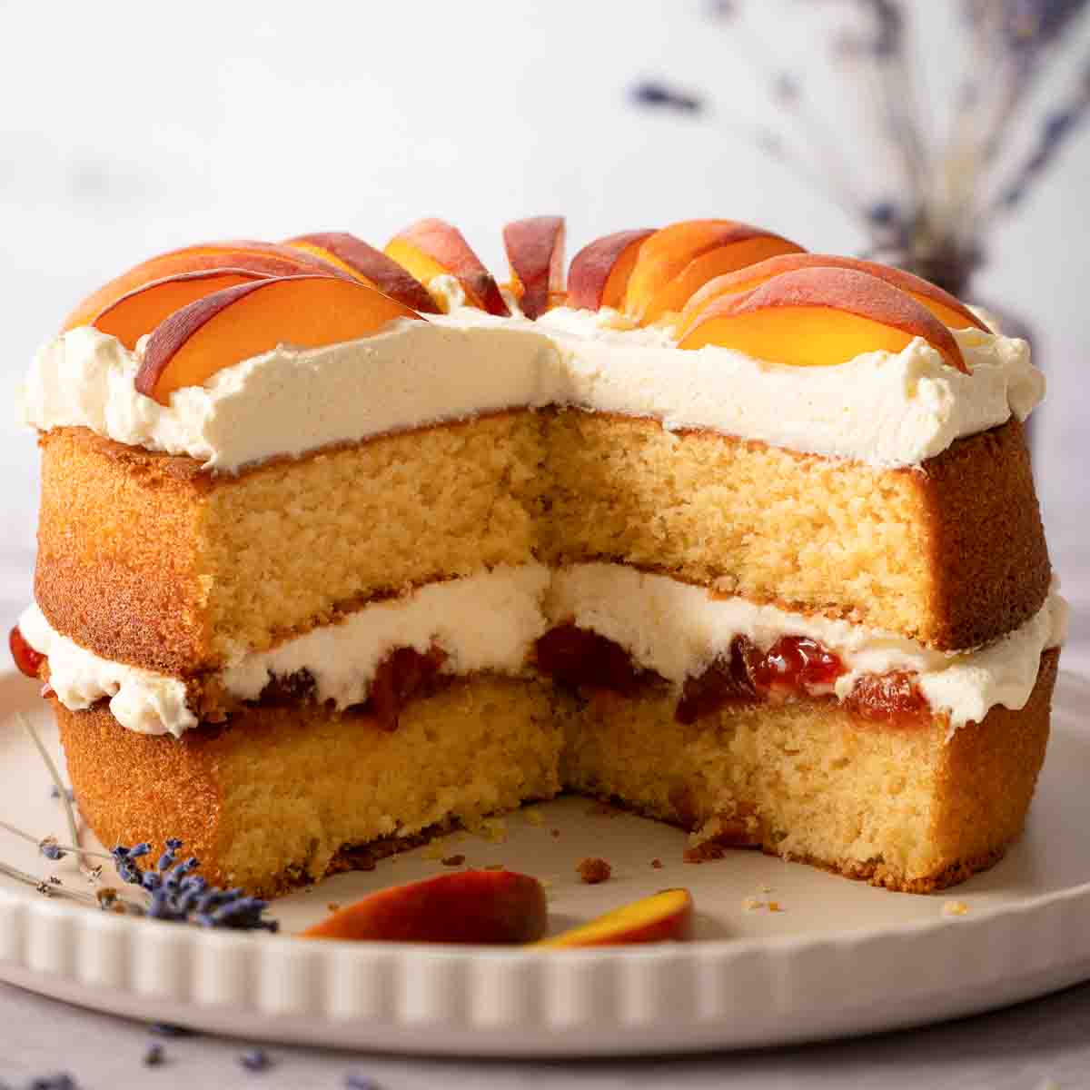 A cut into peaches and cream cake with peach jam and fresh peach slices.