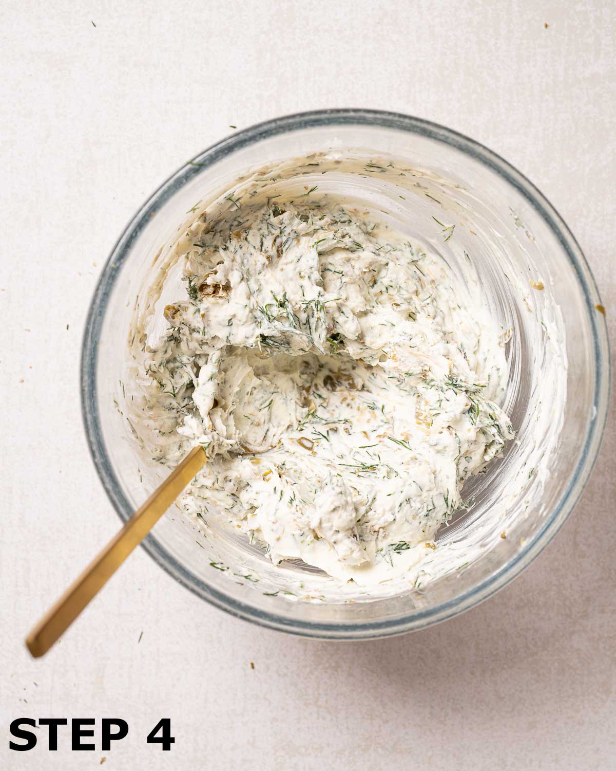 Cream cheese sandwich filling with dill and capers in a mixing bowl.