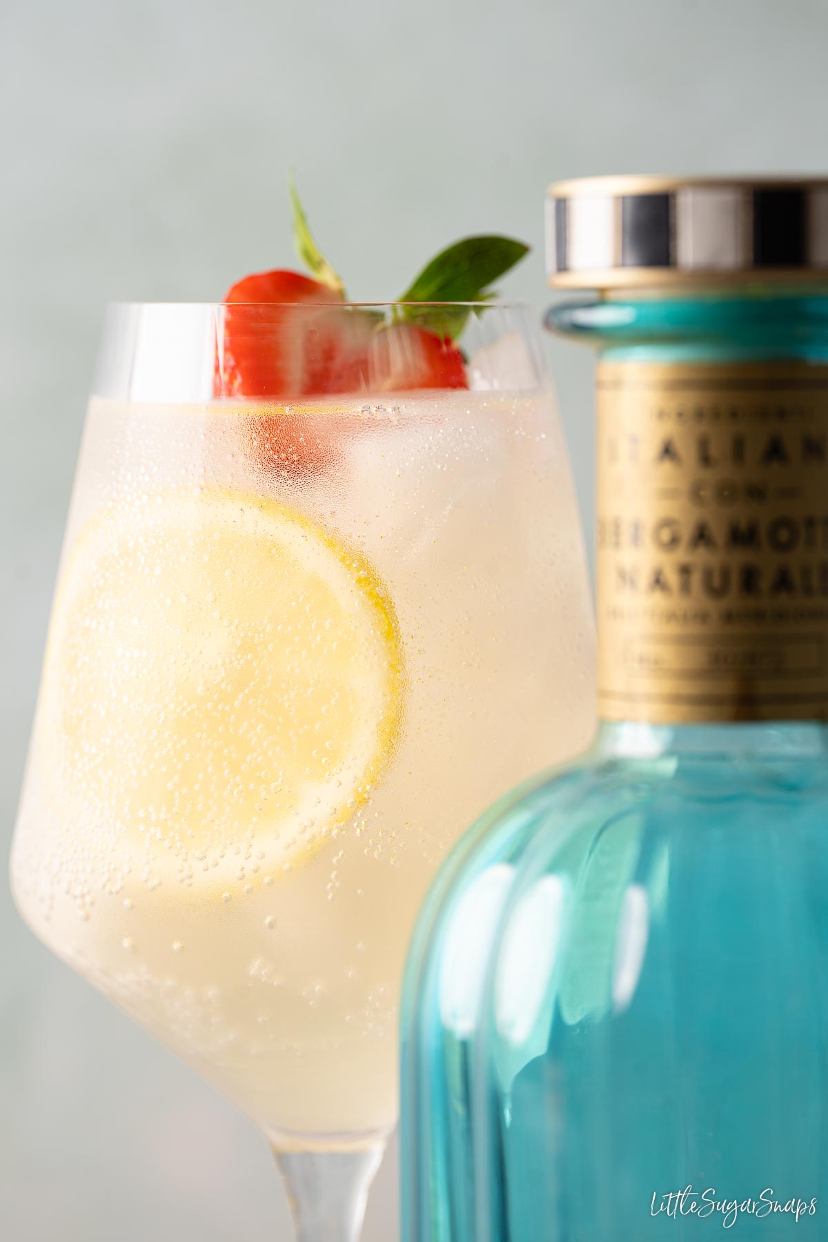 An Italicus spritz cocktail behind a bottle of Italicus liqueur.