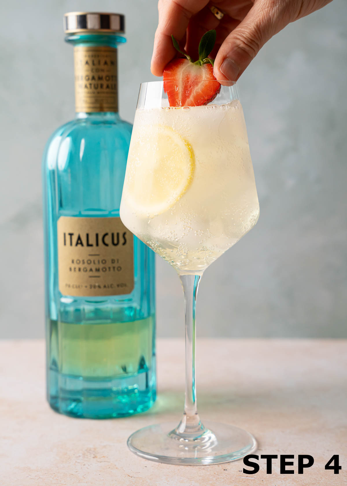 A strawberry garnish being added to an Italicus spritz.