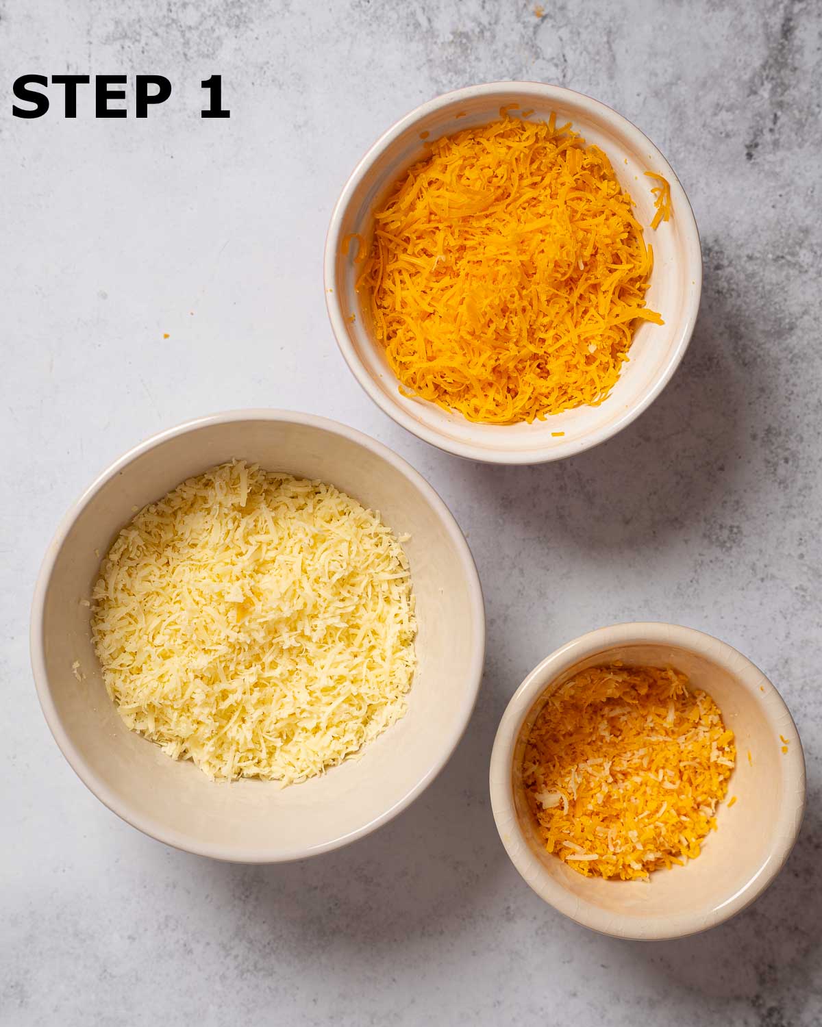 Grated cheese cheese and Red Leicester cheese in bowls.