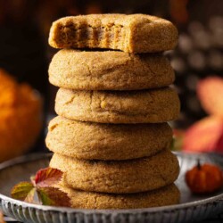 A stack of chewy pumpkin pie spice cookies and the top one has a bite taken out.