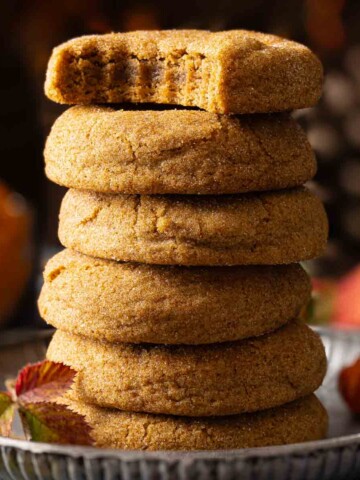A stack of chewy pumpkin pie spice cookies and the top one has a bite taken out.